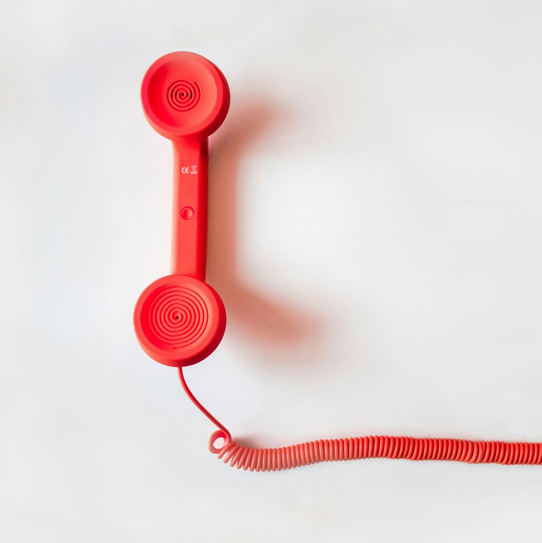 A red telephone on a plain off-white background